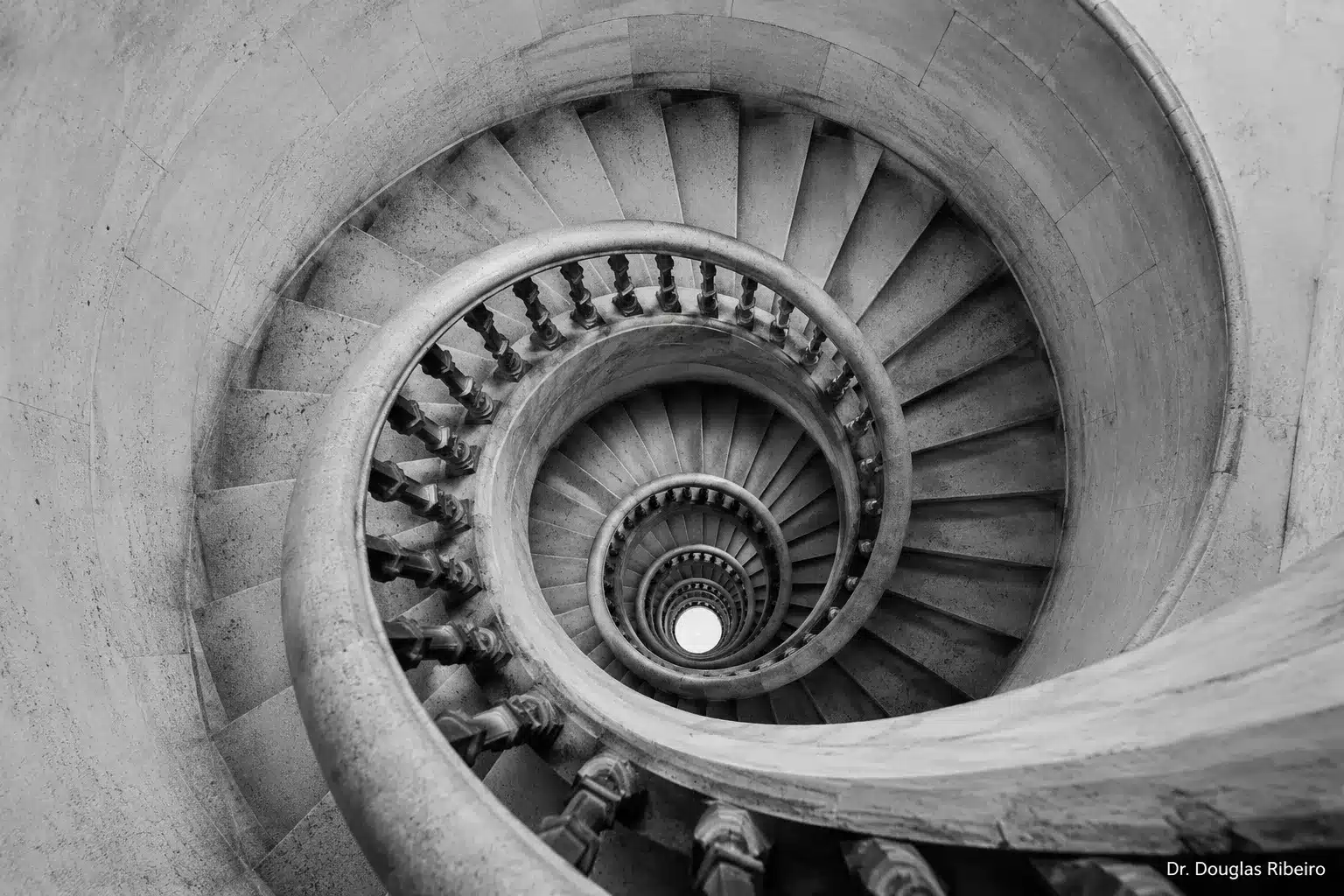 Vista aérea de escada espiral em pedra, representando a estrutura do labirinto e a sensação de desorientação da vertigem