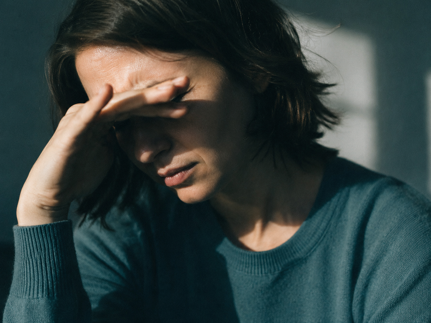Pessoa protegendo os olhos da luz com dor de cabeça, enxaqueca vestibular